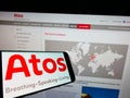 Smartphone with logo of Swedish medical technology company Atos Medical AB on screen in front of website.