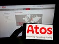 Smartphone with logo of Swedish medical technology company Atos Medical AB on screen in front of website.