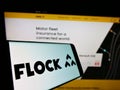 Smartphone with logo of UK insurance company Flock Ltd. on screen in front of business website.