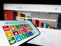 Smartphone with logo of UN Sustainable Development Goals (SDG) on screen in front of website.
