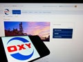 Smartphone with logo of US company Occidental Petroleum Corp (OXY) on screen in front of business website.