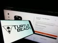 Smartphone with logo of US company Voyetra Turtle Beach Inc. on screen in front of business website.