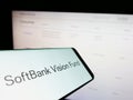 Smartphone with logo of venture capital fund SoftBank Vision Fund on screen in front of business website.