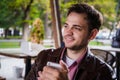 Smartphone man sms texting at outdoor cafe on terrace in summer. Happy casual urban young adult holding phone reading or Royalty Free Stock Photo