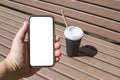 Smartphone mockup on the background of a cup of coffee on a bench in a city park