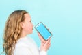 Mockup image of a small beautiful girl holding and showing mobile phone with blue screen on blue background. Royalty Free Stock Photo