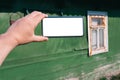 Smartphone mockup in male hand. Against the background of a wooden green wall of the house with an old white retro window Royalty Free Stock Photo