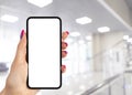 Smartphone mockup in woman hand with business centre background. Modern frameless smartphone mock up with blank white screen. Empt