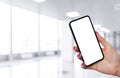 Smartphone mockup in woman hand with business centre background. Modern frameless smartphone mock up with blank white screen. Empt