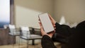 A smartphone mockup in a women`s hands over blurred modern restaurant seating area