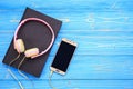 Smartphone, new modern pink music headphone and book on blue woo Royalty Free Stock Photo