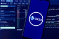 A smartphone with the OKEx logo on the background of the live trading webpage. OKEx dashboard