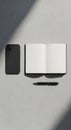 Smartphone, open notebook, and pen arranged on a textured light gray surface. The Royalty Free Stock Photo