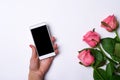 Smartphone and pink roses on a white background. Royalty Free Stock Photo