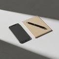Smartphone placed on a light gray surface beside a closed beige notebook and a blac Royalty Free Stock Photo