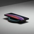 A smartphone is placed on a round wireless charging pad. The phone has a sleek Royalty Free Stock Photo