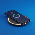 A smartphone is placed on a wireless charging pad set against a blue background. The Royalty Free Stock Photo