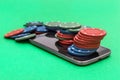 Smartphone with poker chips on green background