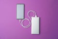 Smartphone and portable charger on purple background. Modern technology Royalty Free Stock Photo