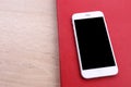 Smartphone on red book and glasses on wooden background