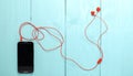Smartphone with red earphone on blue wood background Royalty Free Stock Photo