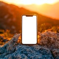 Smartphone resting on a rock with a sunset in the background showing the screen display clearly Royalty Free Stock Photo