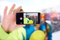 Smartphone screen with three snowboarders taking selfie at ski resort. Friends photographing for social network sharing Royalty Free Stock Photo