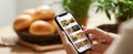 The smartphone showcasing delicious food recipes in a cozy kitchen setting. AI generated image Royalty Free Stock Photo