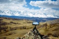 Smartphone on small tripod takes pictures of the mountain range and the clouds above the snowy peaks.  Blurred background, focus Royalty Free Stock Photo