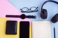 Smartphone,Smartwatch,Black Headphone,Black Wallet,Eyeglasses,Notebook and Black pencil on pink,blue and yellow background Royalty Free Stock Photo