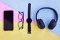 Smartphone,Smartwatch,Black Headphone and Eyeglasses on pink,blue and yellow background Royalty Free Stock Photo