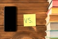 Smartphone and a stack of books on a wooden table. The concept of getting information from books or the Internet