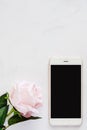 Smartphone with sweet pink rose on white marble background