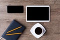 Smartphone and tablet with black screens on a wooden background with cup of black coffee. Blue-black planner and two pencils on it