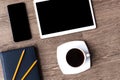 Smartphone and tablet with black screens on a wooden background with cup of black coffee. Blue-black planner and two pencils on it