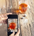 Smartphone take photos of tea and grape on wooden background, vibrant concept