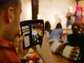 A smartphone on a tourist`s hands taking a photograph of Northern Thai dancing performing on a stage