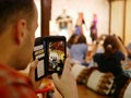 A smartphone on a tourist`s hands taking a photograph of Northern Thai dancing performing on a stage