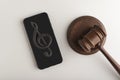 Smartphone with treble clef sign on display and judges hammer. Illegal use of music concept. Digital piracy Royalty Free Stock Photo