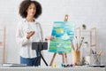 Smartphone with tripod close up. Woman draws picture in studio interior blurry