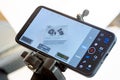Smartphone on tripod filming product packaging in home studio, mobile screen with video app interface, histogram and levels, Royalty Free Stock Photo