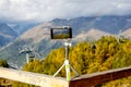 Smartphone on a tripod in the mountains, a lift and a rainbow on the background.