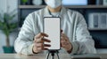 Smartphone on tripod with a person in white lab coat holding it, blurred background.