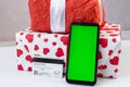 Smartphone with vertical green screen, bank card and Christmas gifts on the table. Online shopping festive internet concept.