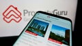 Smartphone with webpage of online property company PropertyGuru Pte. Ltd. on screen in front of business logo.