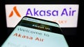 Smartphone with website of airline SNV Aviation Private Limited (Akasa Air) on screen in front of logo.
