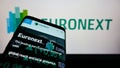 Smartphone with website of financial services company Euronext N.V. on screen in front of business logo.