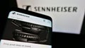 Smartphone with website of German audio company Sennheiser electronic GmbH Co. KG on screen in front of logo.