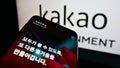 Smartphone with website of South Korean company Kakao Entertainment Corp. on screen in front of business logo.