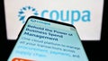 Smartphone with website of spend management company Coupa Software Inc. on screen in front of business logo.